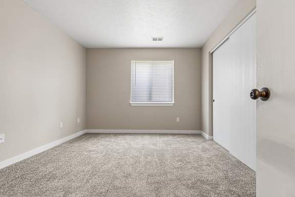 A room with a carpeted floor and a door on the right side.