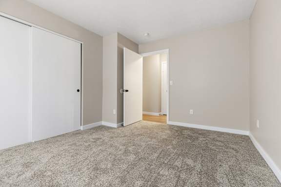 A room with a carpeted floor and two doors.