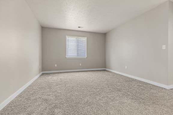 A room with a carpeted floor and a window.