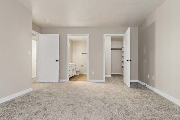 A spacious room with carpeted floor and white walls.