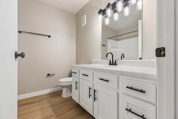 A bathroom with a white counter top and a white toilet.
