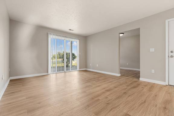 A room with wooden floors and a sliding glass door leading outside.