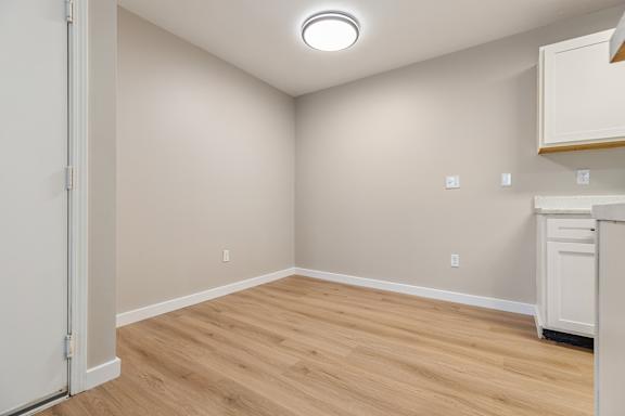 A room with a wooden floor and a white cabinet.