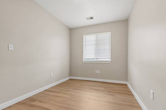 A room with a window and wooden flooring.