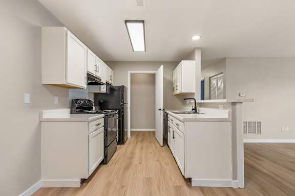 A kitchen with black appliances and white cabinets.