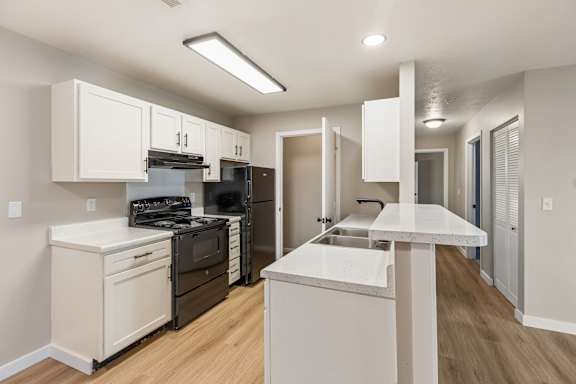 A kitchen with white cabinets and a black refrigerator.
