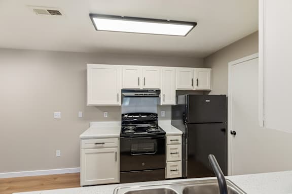 A kitchen with black appliances and white cabinets.
