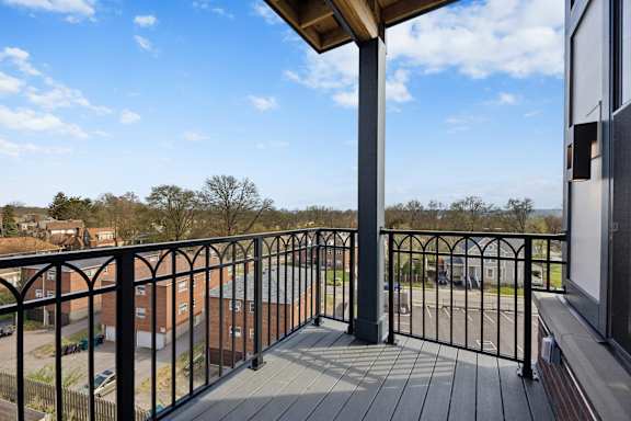 A balcony with a black railing and a wooden post.