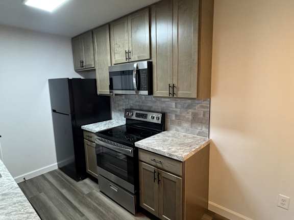 A kitchen with black appliances and wooden cabinets.