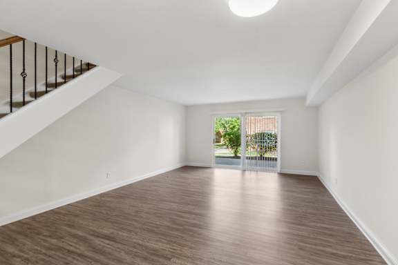 A room with wooden flooring and a staircase with a railing.