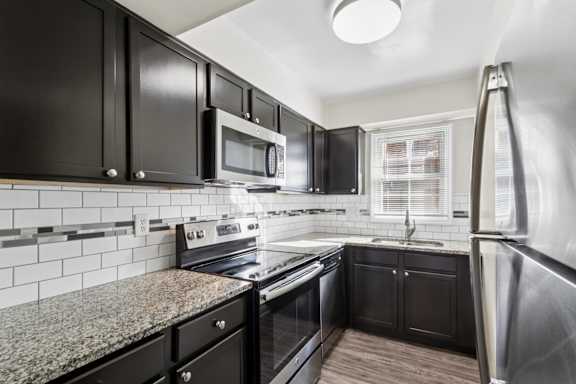 A kitchen with black cabinets and stainless steel appliances.
