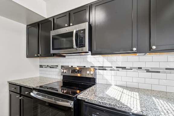 A kitchen with black cabinets and a black oven.