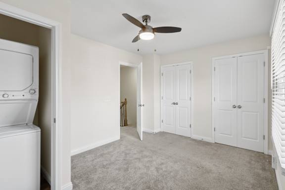 A white bathroom with a toilet and a fan.