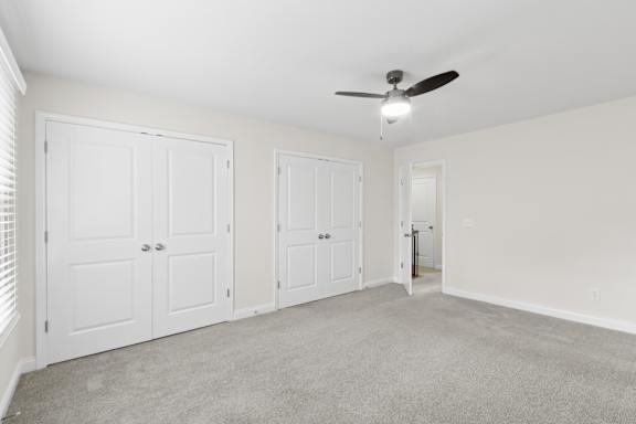 A room with a ceiling fan and three doors.