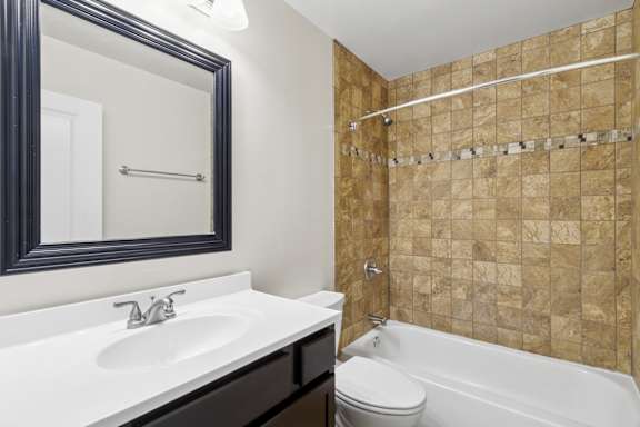 A bathroom with a sink, toilet, and tiled shower.