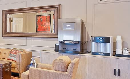 A living room with a couch, chair, and a coffee maker.