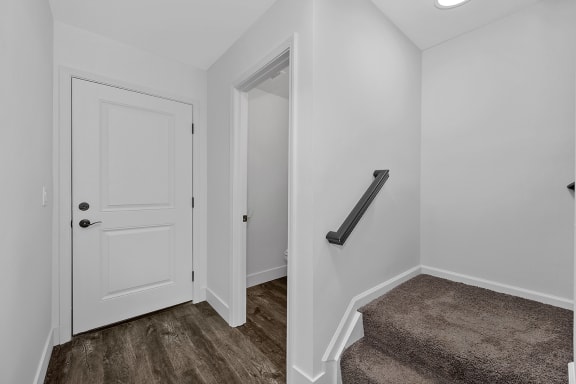 a small entryway with a white door and a carpeted stairwell with a at Ivy Hills Living Spaces, Cincinnati, 45244
