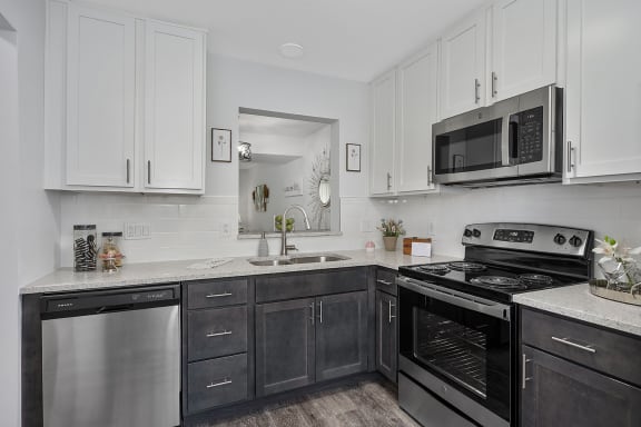 a kitchen with white cabinets and a stove and a microwave at Ivy Hills Living Spaces, Cincinnati