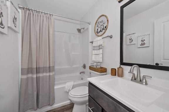a bathroom with a shower curtain and some toilets and a mirror at Ivy Hills Living Spaces, Cincinnati, Ohio