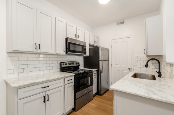 a kitchen with white cabinets and stainless steel appliances