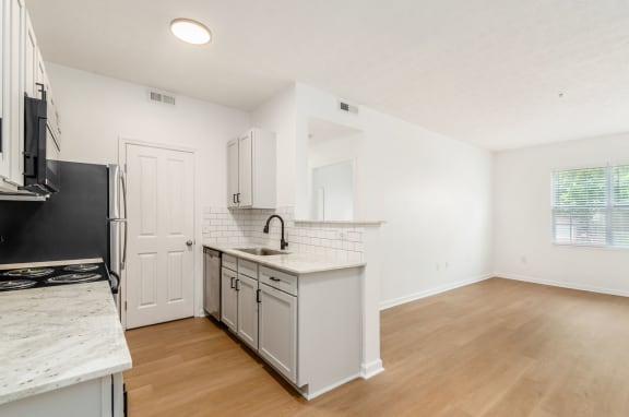 an empty kitchen with white cabinets and a counter top