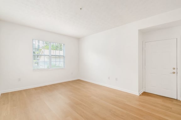 a bedroom with white walls and wood floors and a door