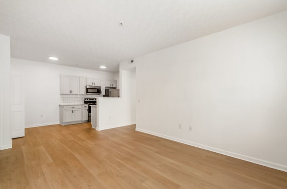 an empty living room and kitchen with white walls and wood floors