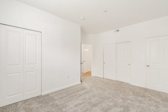 an empty bedroom with white doors and carpeting