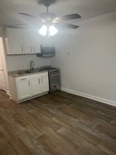 A kitchen with white cabinets and a wood floor.