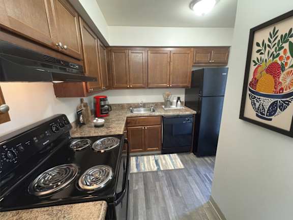 A kitchen with a black stove top oven and a black refrigerator.
