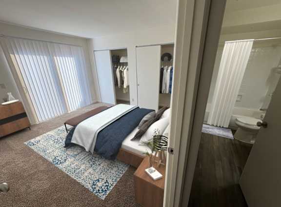 A bedroom with a bed, a nightstand, and a window with blinds.