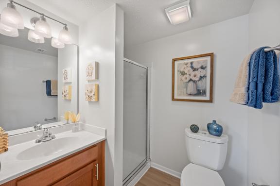 A bathroom with a toilet, sink, mirror, and a painting on the wall.