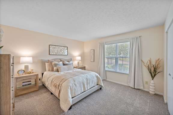 A bedroom with a large bed and a window with curtains.