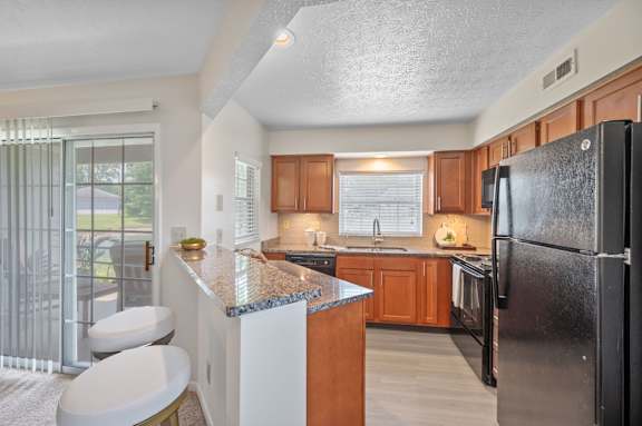A kitchen with a black refrigerator and wooden cabinets.