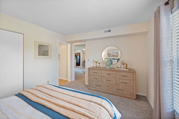 A bedroom with a bed, dresser, and mirror.