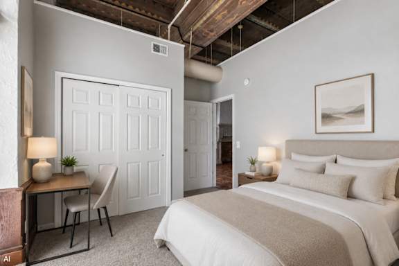 A bedroom with a bed, desk, chair, and a painting on the wall.