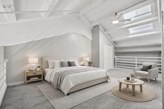A bedroom with a large bed and a chair.