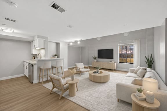 A modern living room with a kitchen area in the background.