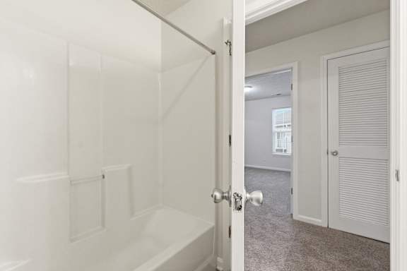 A white bathroom with a tub and a door.