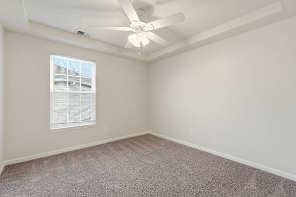 A room with a ceiling fan and a window with blinds.