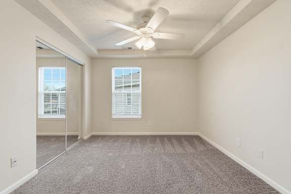 A room with a ceiling fan and carpeted floor.