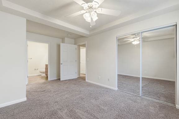 A spacious room with a ceiling fan and carpeted floor.