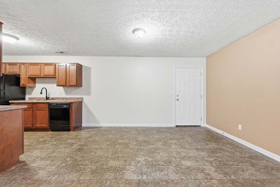 A kitchen area with a black refrigerator, wooden cabinets, and a black oven.
