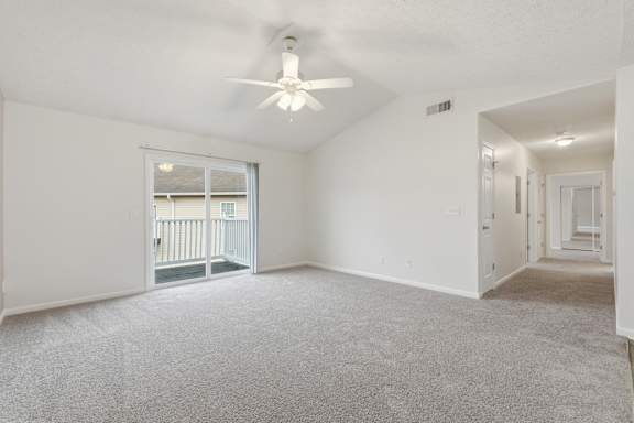 A spacious room with a ceiling fan and carpeted floor.