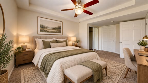 A bedroom with a large bed, a ceiling fan, and a painting on the wall.