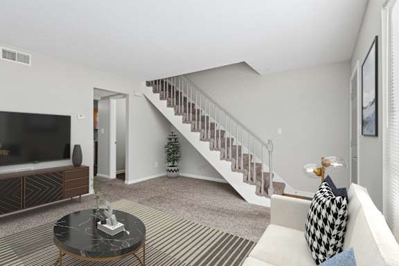 A living room with a staircase in the background.