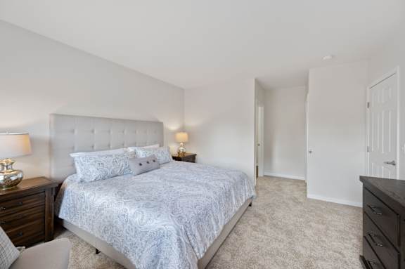 A bedroom with a large bed and a nightstand with a lamp. at Roebling Row, Covington, KY, 41011-1720