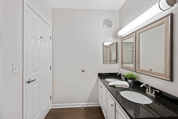 A bathroom with a white door, a black countertop, and a mirror above the sink. at Roebling Row, Covington, KY