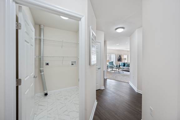 A white hallway with a door on the left and a view into a living room on the right. at Roebling Row, Covington, KY