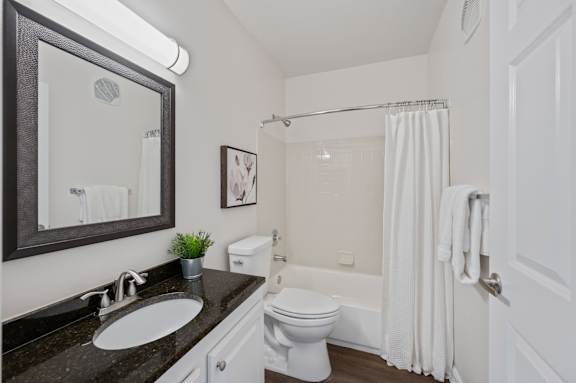 A bathroom with a white toilet, sink, and shower curtain. at Roebling Row, Covington
